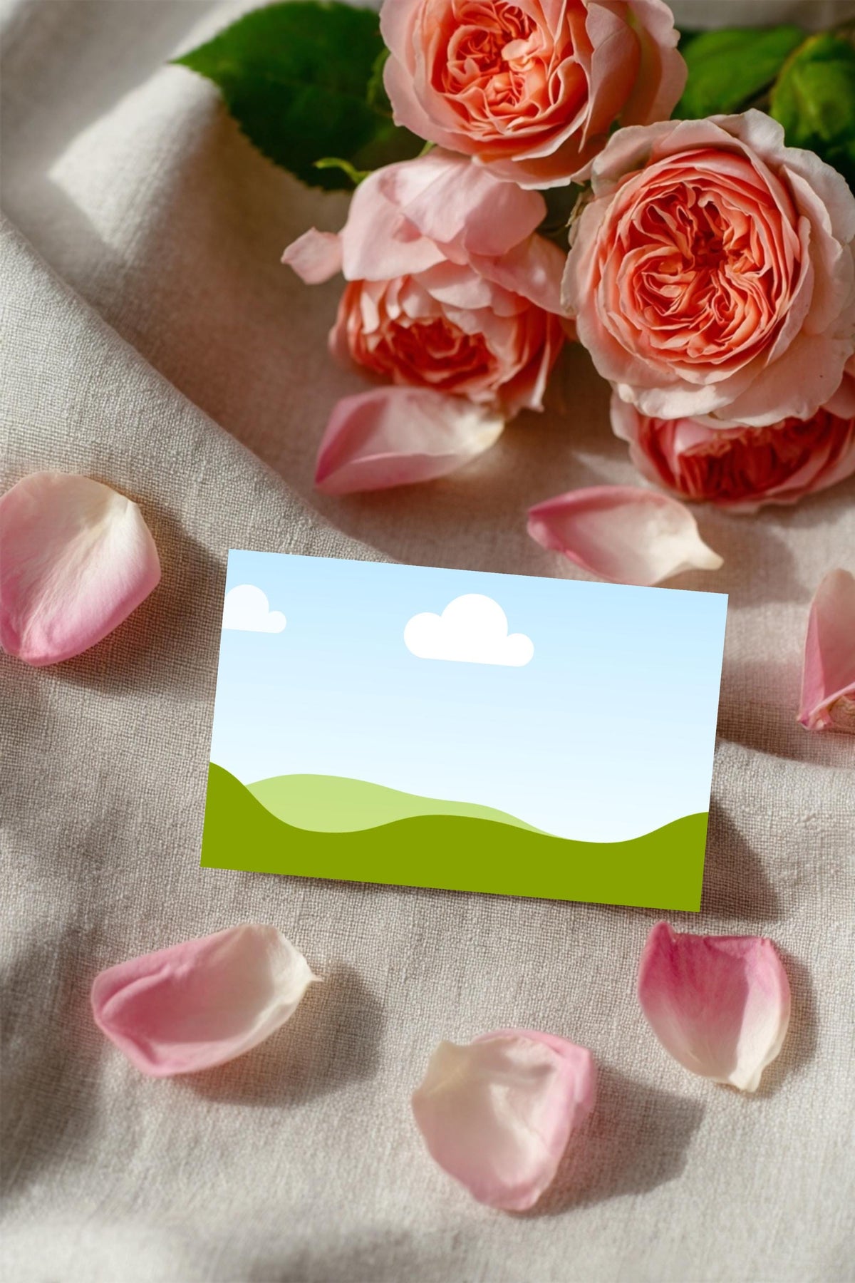 Garden wedding place card close-up with cloud-and-hills design among rose petals