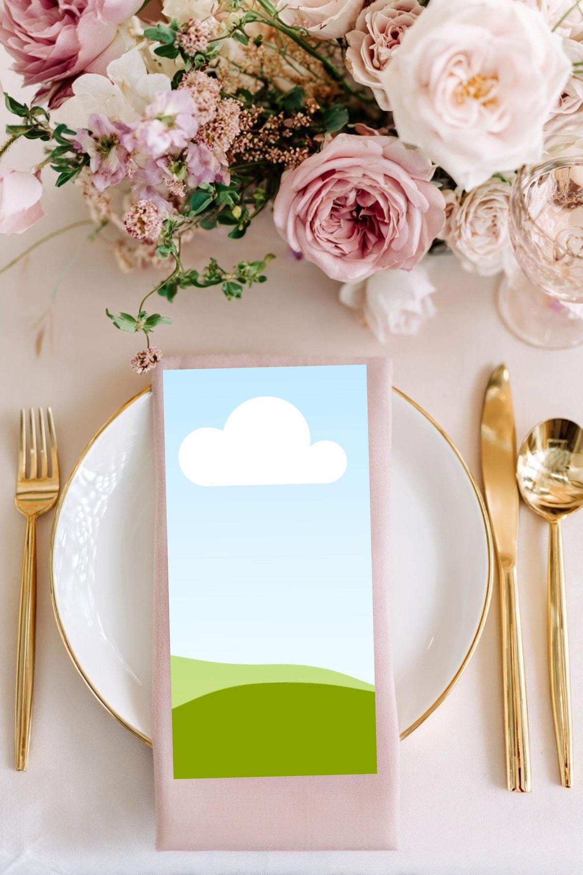 Garden wedding place card mockup with cloud-and-hills design on pink napkin with gold cutlery